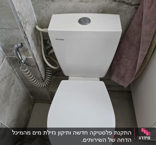 אסלה לבנה עם מיכל הדחה בחדר אמבטיה